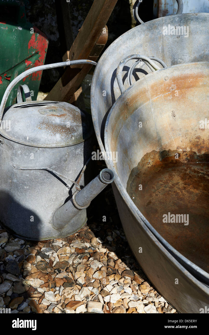 An old tin bath and watering can in the evening sun. Stock Photo