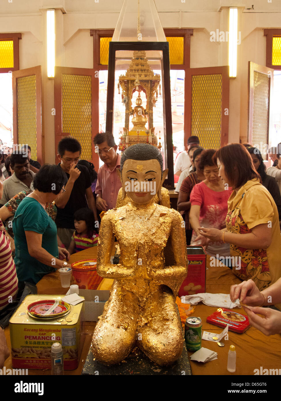 Buddhist worshippers apply gold leaf to a statue of Buddha on Vesak Day