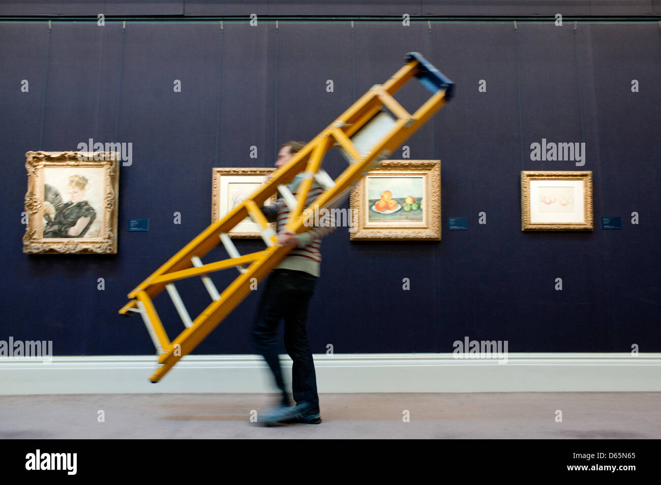 London, UK. 12th April 2013. A Sotheby's employee walks by with a ladder in front of  impressionist paintings including 'Les Pommes' by Paul Cezanne that will go on sale at Sotheby’s New York in May 2013. The Blockbuster sales at include works by Richter, Modigliani, Picasso, Rodin, Bacon, Cezanne. Credit: Piero Cruciatti / Alamy Live News Stock Photo