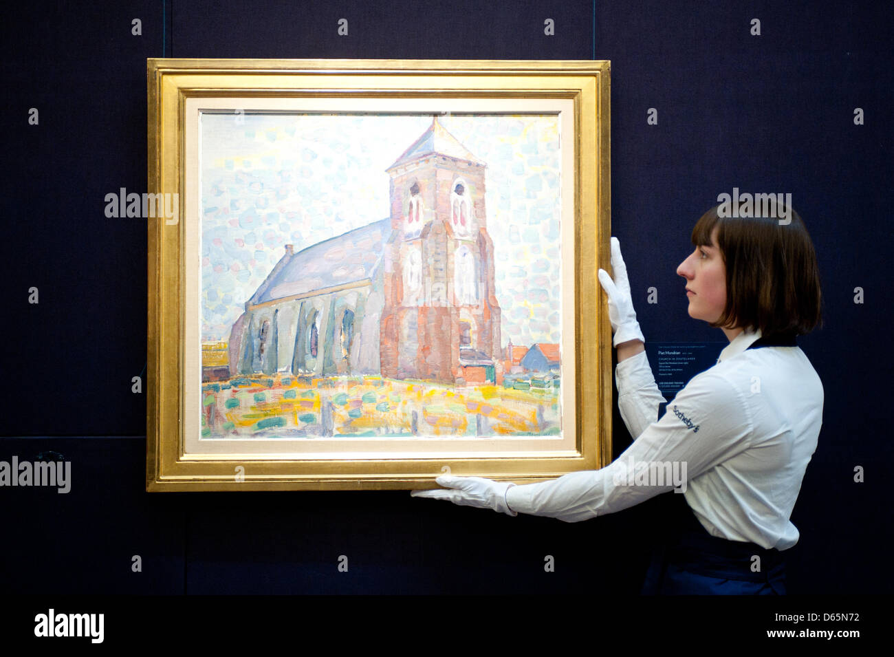 London, UK. 12th April 2013. A Sotheby's employee poses in front of  Piet Mondrian 'Church in Zouteland' (Est. $500.000-700.000). The work will go on sale at Sotheby’s New York in May 2013. The Blockbuster sales at include works by Richter, Modigliani, Picasso, Rodin, Bacon, Cezanne. Credit: Piero Cruciatti / Alamy Live News Stock Photo