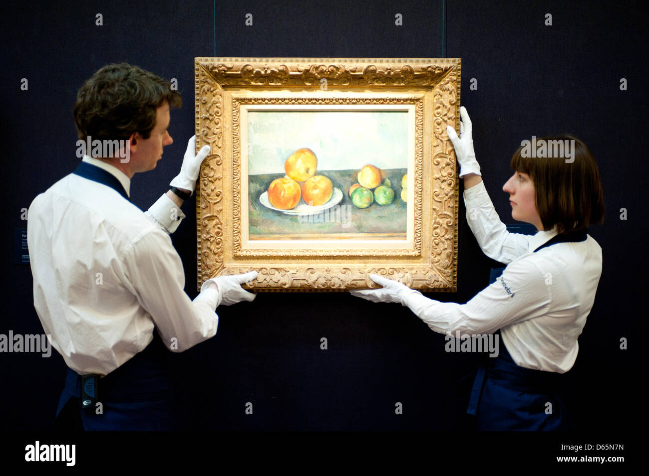 London, UK. 12th April 2013. Sotheby's employees pose in front of 'Les Pommes' by Paul Cezanne (Est. $25-35 million). The work will go on sale at Sotheby’s New York in May 2013. The Blockbuster sales at include works by Richter, Modigliani, Picasso, Rodin, Bacon, Cezanne. Credit: Piero Cruciatti / Alamy Live News Stock Photo