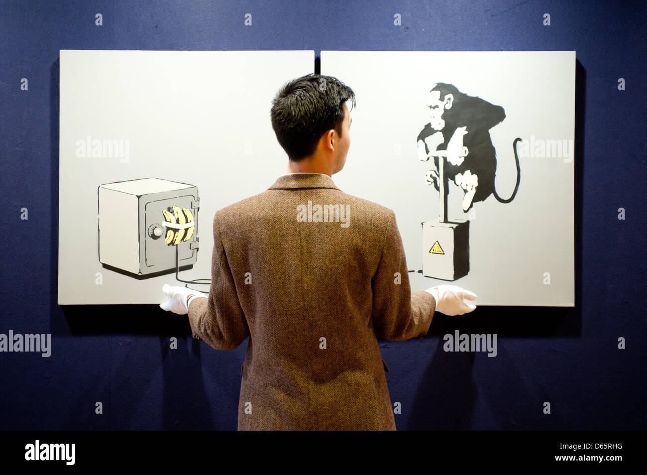 London, UK. 12th April 2013. a sales assistant holds a diptych canvas entitled “Monkey Detonator” by Banksy during the 'Urban Art' auction preview at Bonhams. The work displays his typical sense of surrealist humour. Measuring 152 by 76 cm., this painting carries an estimate of £70,000-100,000. Credit: Piero Cruciatti / Alamy Live News Stock Photo