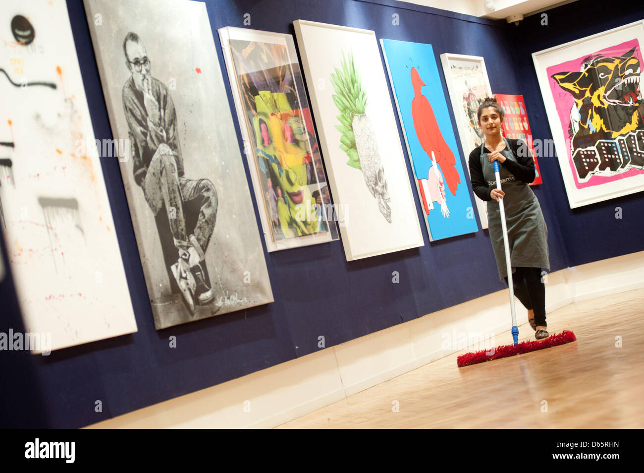 London, UK. 12th April 2013. a Bonhams sales assistant works next to canvas during the 'Urban Art' auction preview. Credit: Piero Cruciatti / Alamy Live News Stock Photo