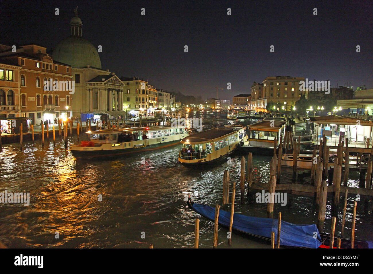 Vaporetti or water buses next to the pontoon or stop at Ferrovia station on the Grand Canal at night Venice Italy Stock Photo