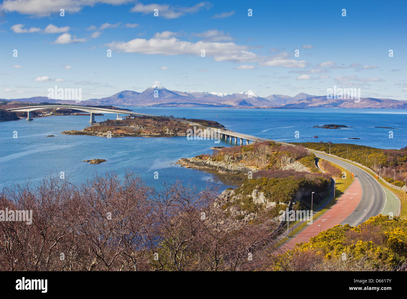 SKYE BRIDGE WITH SNOW CAPPED CUILLIN MOUNTAIN RANGE AND LOCH ALSH ON AN EARLY SPRING DAY IN THE WESTERN HIGHLANDS OF SCOTLAND Stock Photo
