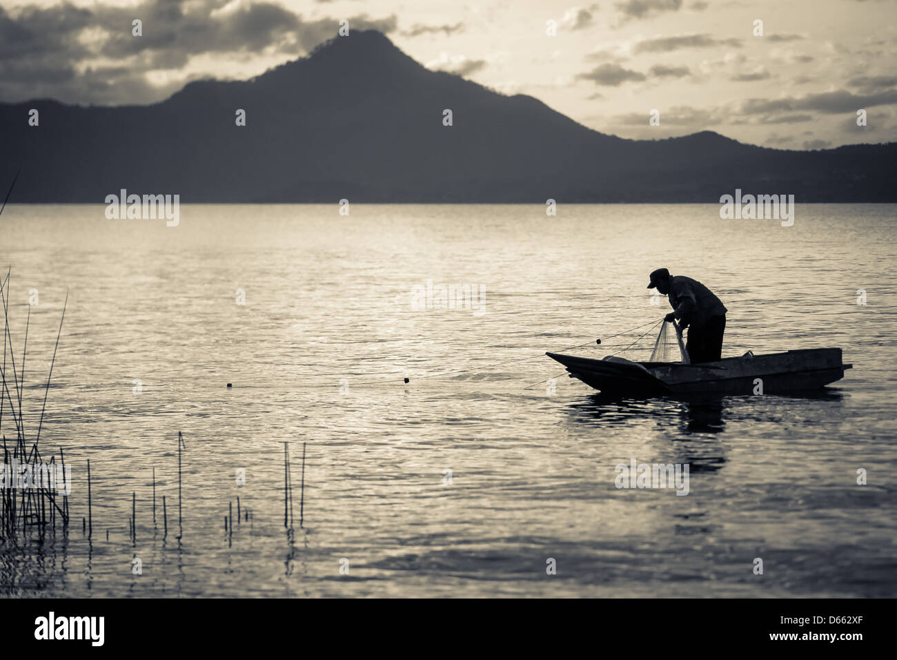 Silhouette of a fisherman in a small boat on a lake. Black and white ...