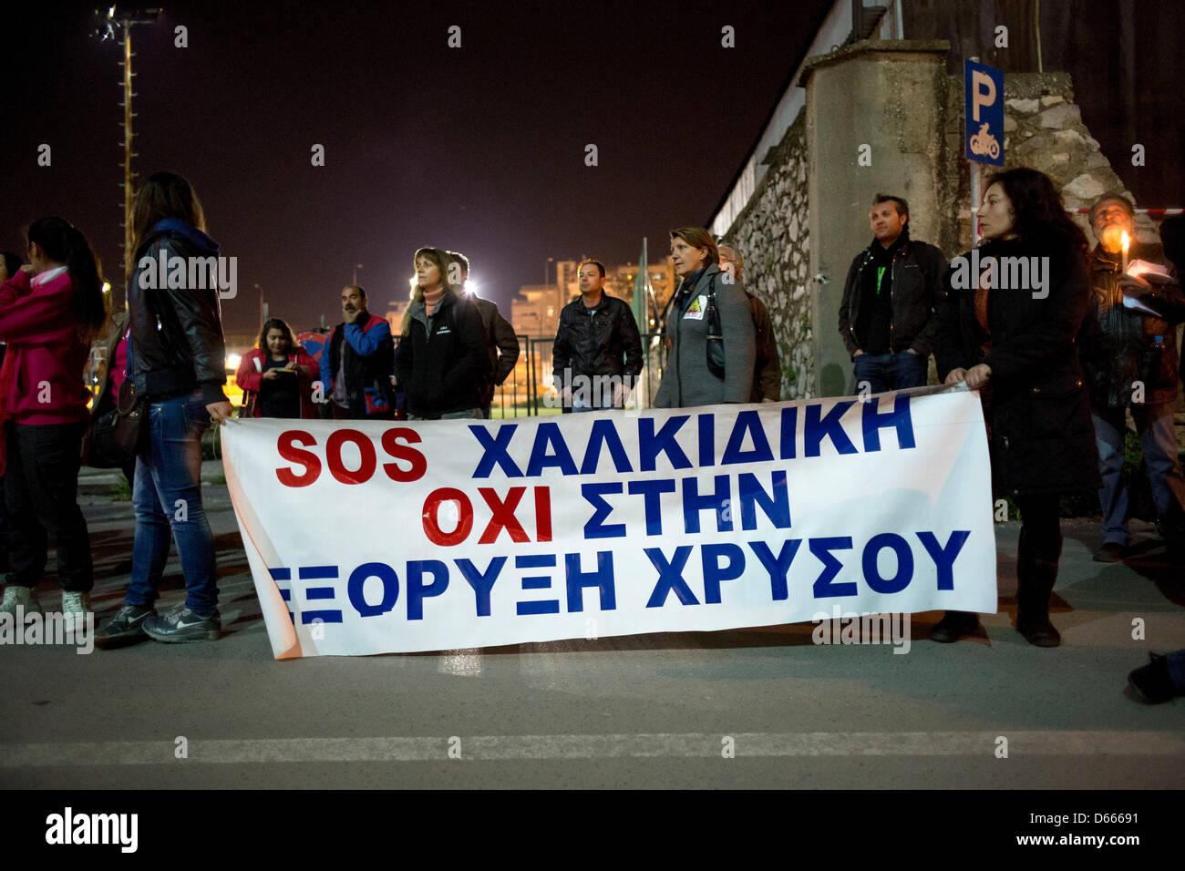 Protesters holds banner that reads 'SOS Halkidiki, No to Gold mining'. Residents of Ierissos village, Greece's northern Halkidiki peninsula, with candles shout slogans during a rally outside police headquarters in the northern Greek port city of Thessaloniki late Friday, April 12, 2013 Stock Photo