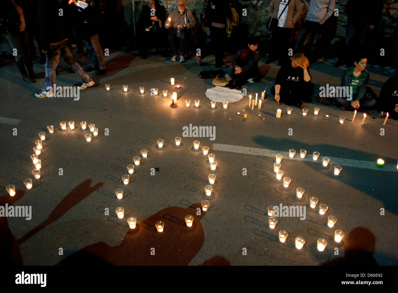 Residents of Ierissos village, Greece's northern Halkidiki peninsula, with candles make the word SOS gather during a rally outside police headquarters in the northern Greek port city of Thessaloniki late Friday, April 12, 2013 Stock Photo