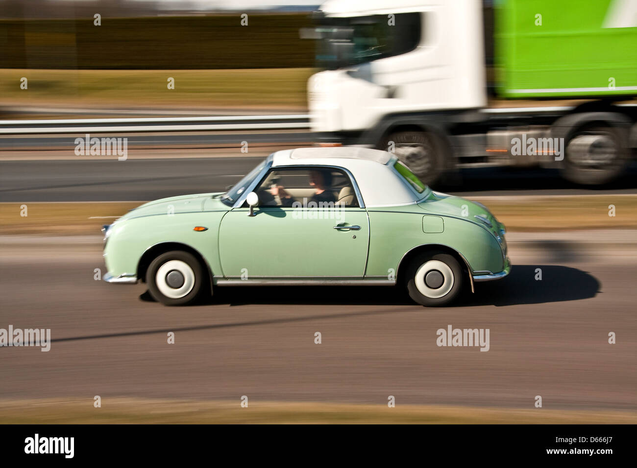 Retro 1960`s style Nissan Figaro Japanese car being overtaken by a ... Retro 1960`s style Nissan Figaro Japanese car being overtaken by a ...