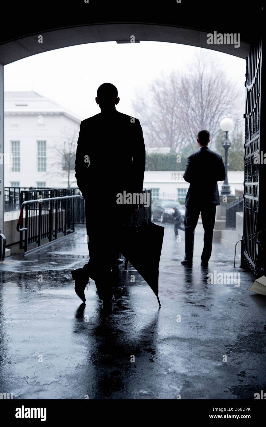 US President Barack Obama waits for a heavy rain to pass before crossing West Executive Avenue from the Eisenhower Executive Office Building to the West Wing of the White House March 12, 2013 in Washington, DC. Stock Photo