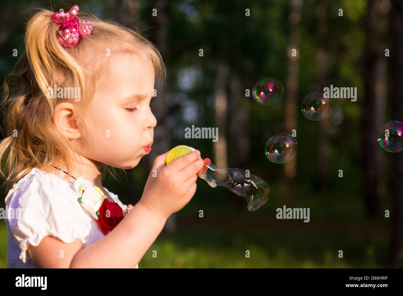 Beautiful little girl blowing soap bubbles in park outdoor Stock Photo ...
