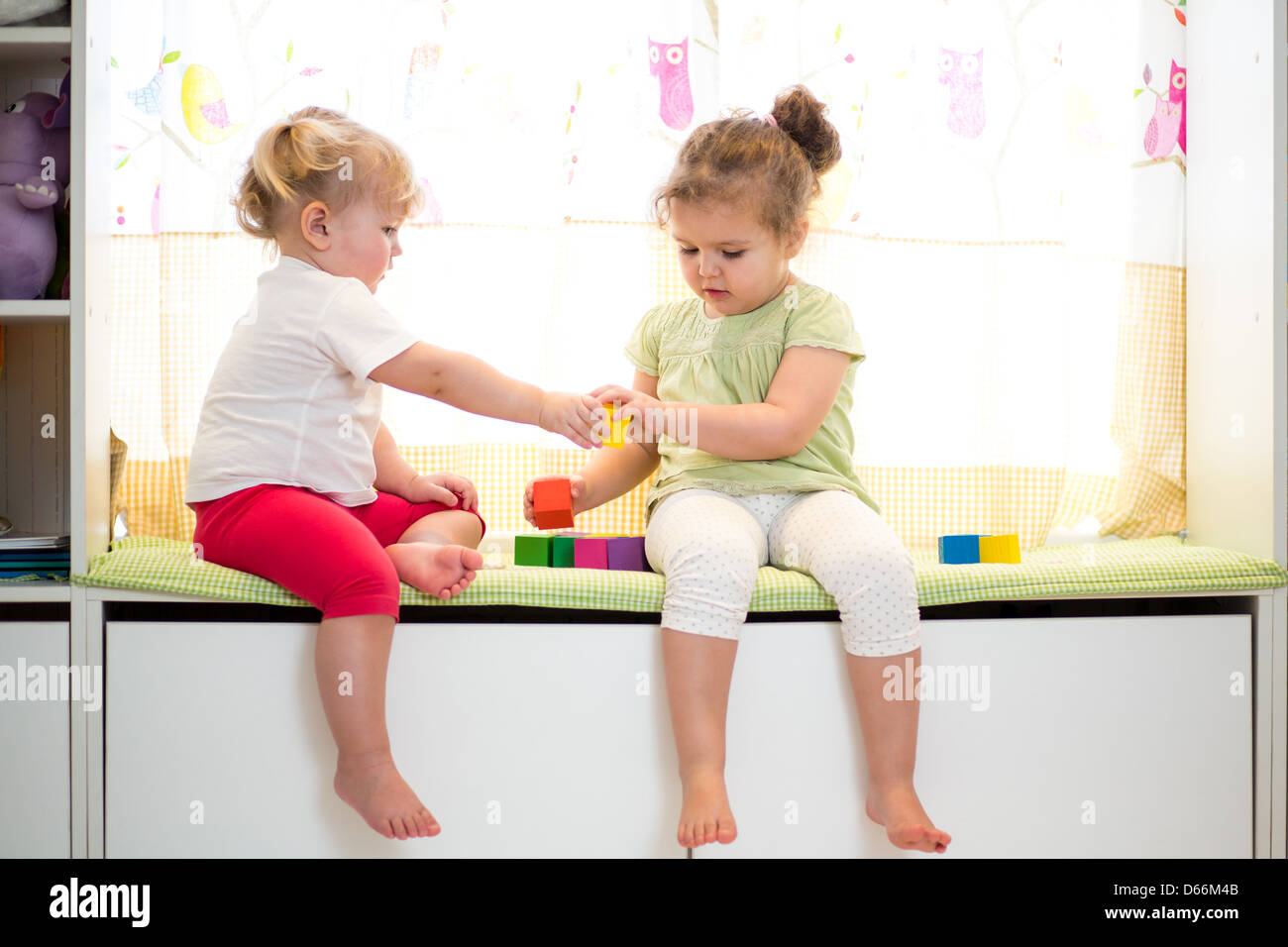 two kids sisters play together indoors Stock Photo