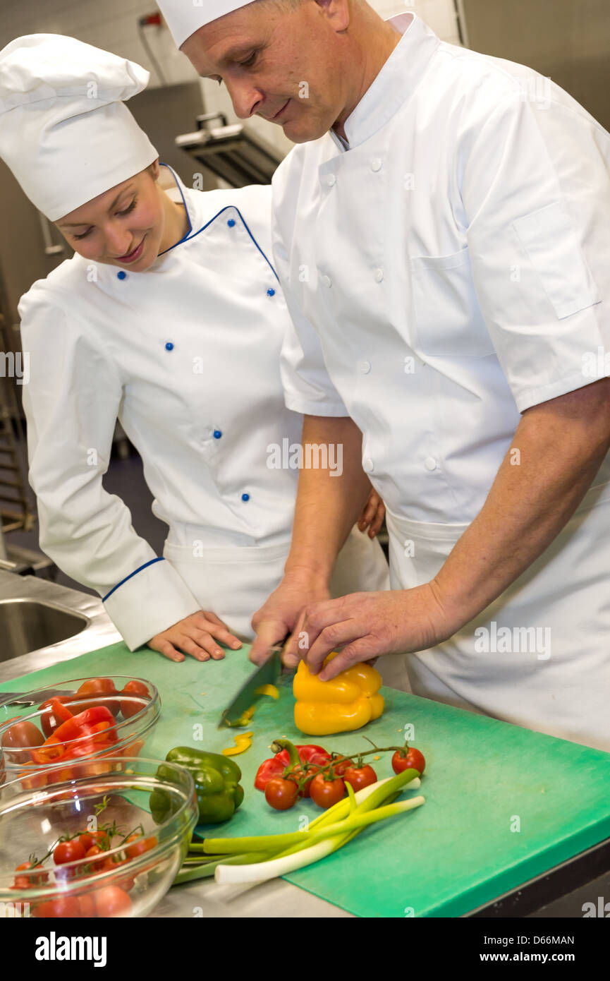 Apprentice learning cutting vegetables from chef in kitchen Stock Photo ...