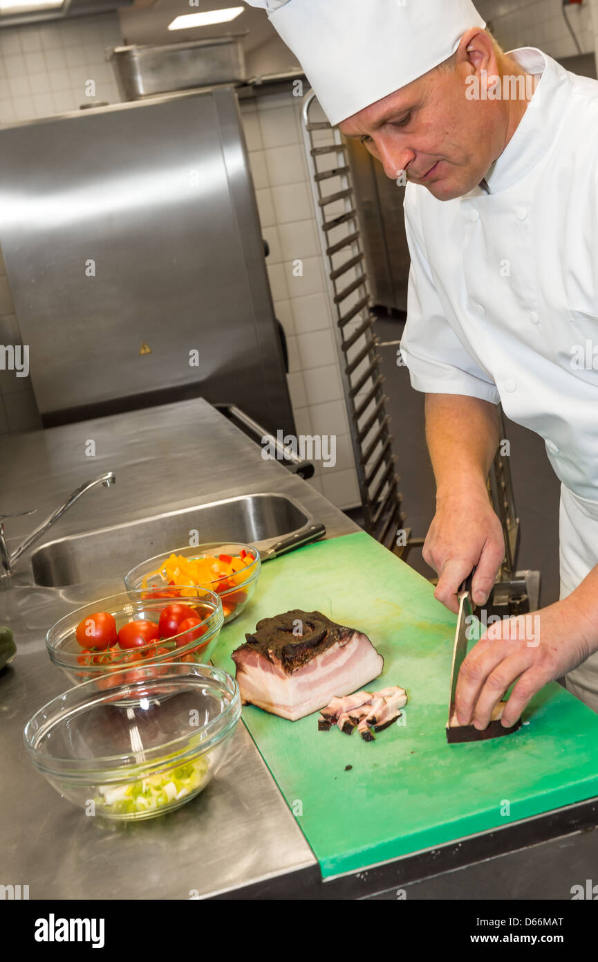 Busy male cook cutting meat in restaurant's kitchen Stock Photo