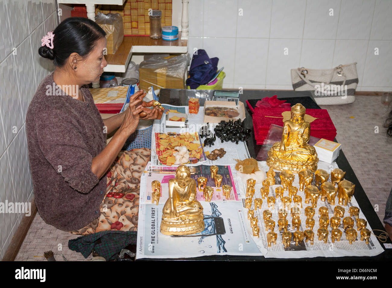 Woman applying gold leaf to souvenirs, King Galon Gold Leaf Workshop, Mandalay, Myanmar, (Burma) Stock Photo