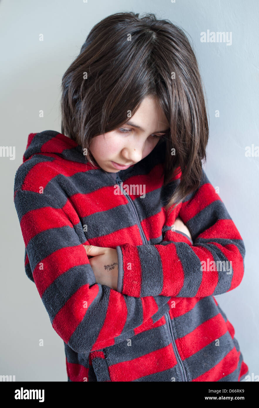 Young white dark-haired girl looking sad, angry, vulnerable and upset, looking at the camera and away from camera wearing a red and grey sweatshirt Stock Photo