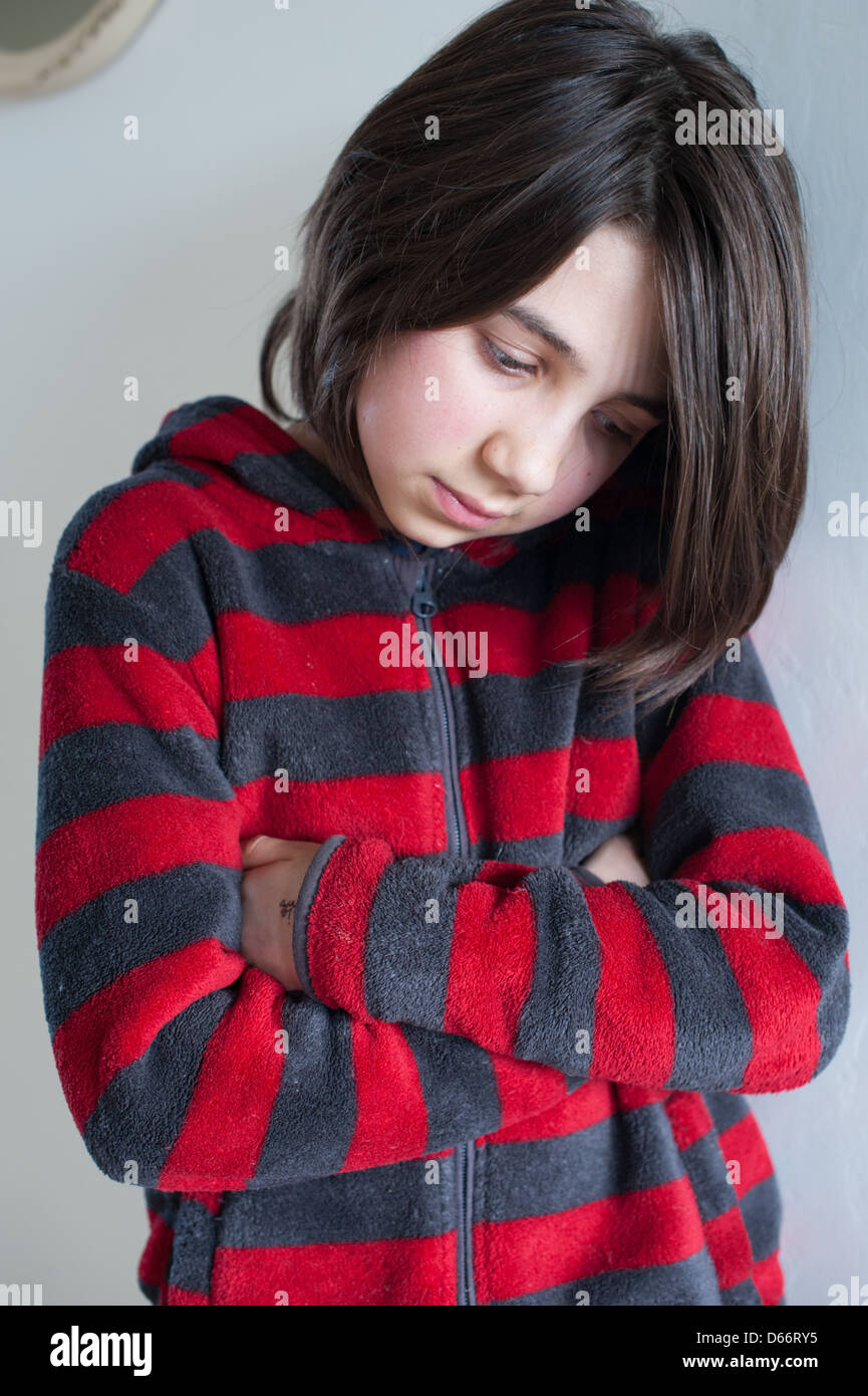 Young white dark-haired girl looking sad, angry, vulnerable and upset, looking at the camera and away from camera wearing a red and grey sweatshirt Stock Photo