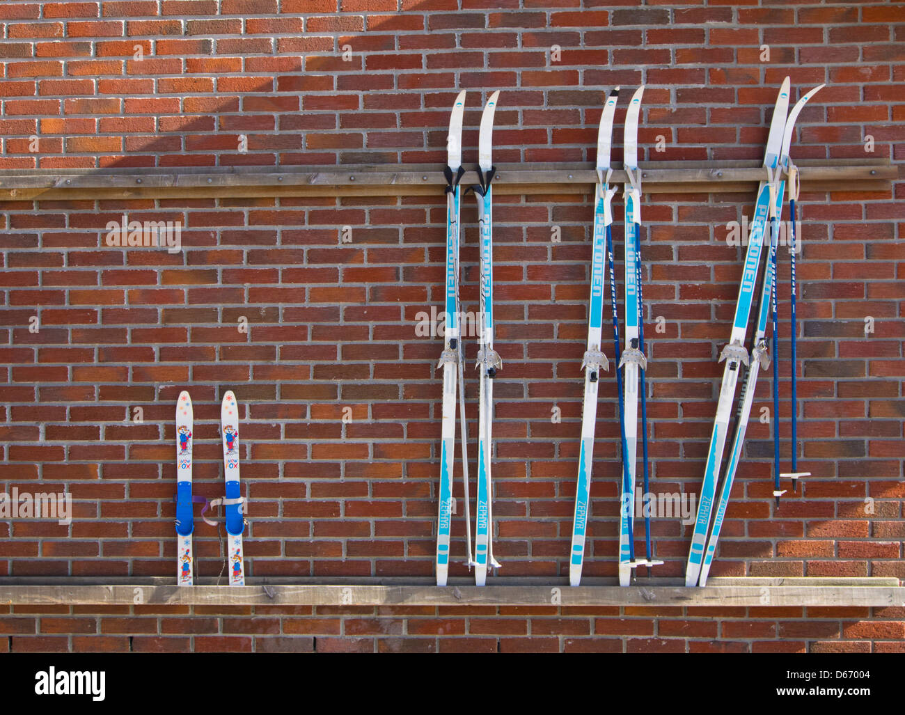 Skis on red brick wall, 3 pairs for grown ups one for kids, Oslo Norway Stock Photo