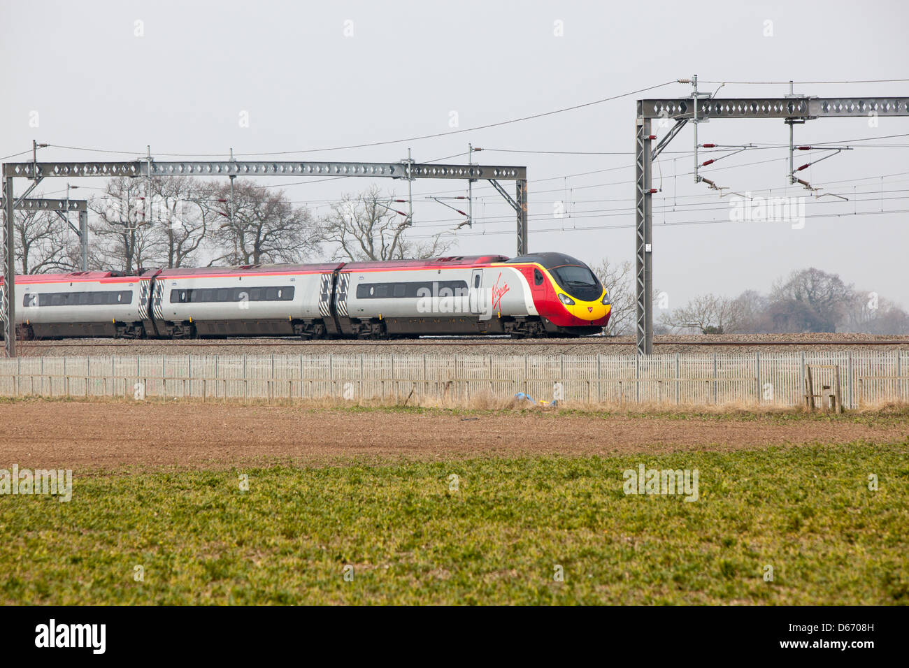 A Virgin train running through the countryside adjacent to farmland. Stock Photo
