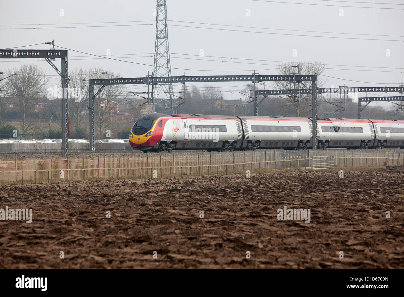 A Virgin train running through the countryside adjacent to farmland. Stock Photo