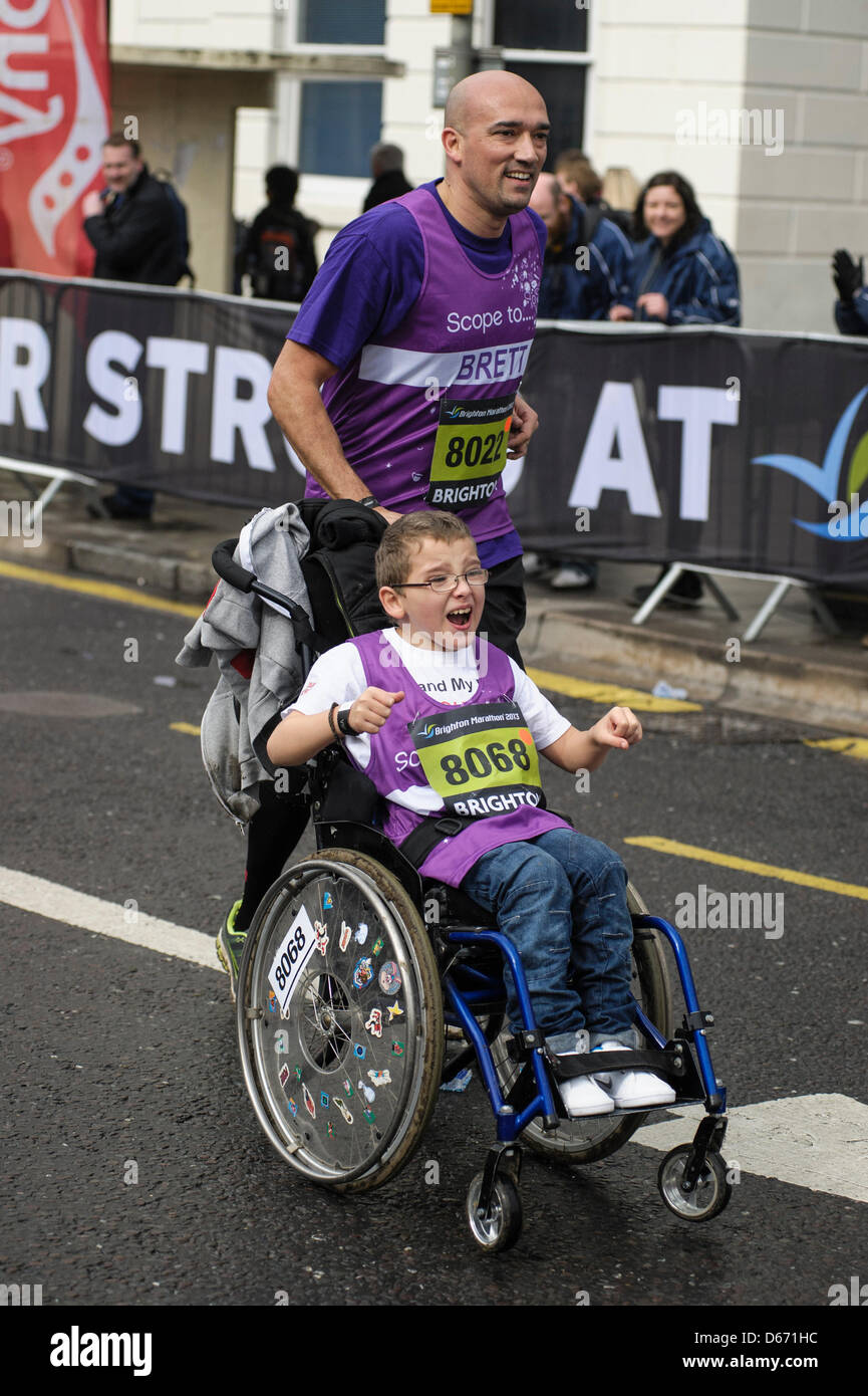 Brighton, UK, 14/04/2013 : Brighton Marathon. A man pushes young boy around the course in a wheelchair. Picture by Julie Edwards Stock Photo