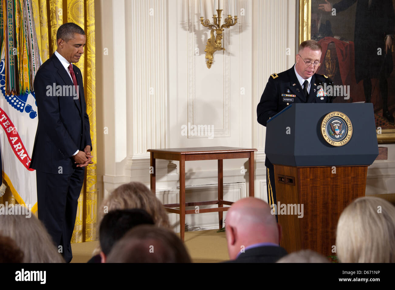 US President Barack Obama bows his head during a moment of prayer during the posthumous Medal of Honor award ceremony for US Army Chaplain Capt. Emil Kapaun in the East Room of the White House April 11, 2013 in Washington, DC. Father Kapaun was honored for his heroism during combat at Unsan, Korea and later died as a POW. Stock Photo