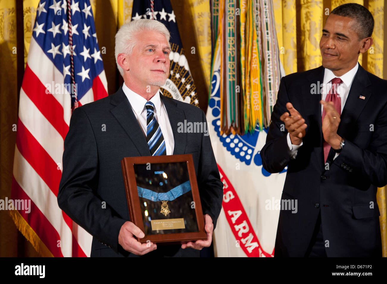 US President Barack Obama awards the Medal of Honor to US Army Chaplain Capt. Emil Kapaun, accepted posthumously by his nephew Ray, left, during a ceremony in the East Room of the White House April 11, 2013 in Washington, DC. Father Kapaun was honored for his heroism during combat at Unsan, Korea and later died as a POW. Stock Photo