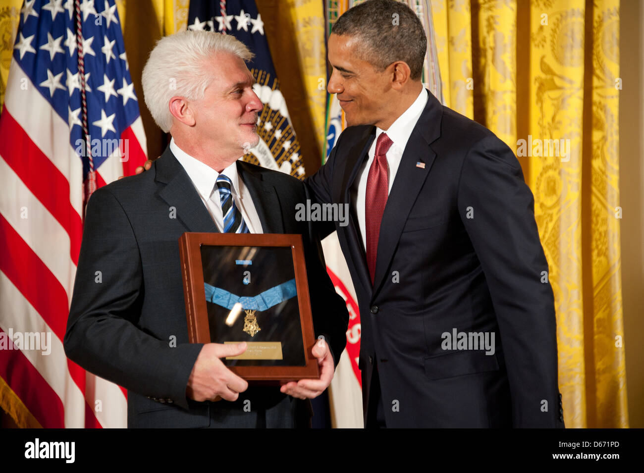 US President Barack Obama awards the Medal of Honor to US Army Chaplain Capt. Emil Kapaun, accepted posthumously by his nephew Ray, left, during a ceremony in the East Room of the White House April 11, 2013 in Washington, DC. Father Kapaun was honored for his heroism during combat at Unsan, Korea and later died as a POW. Stock Photo