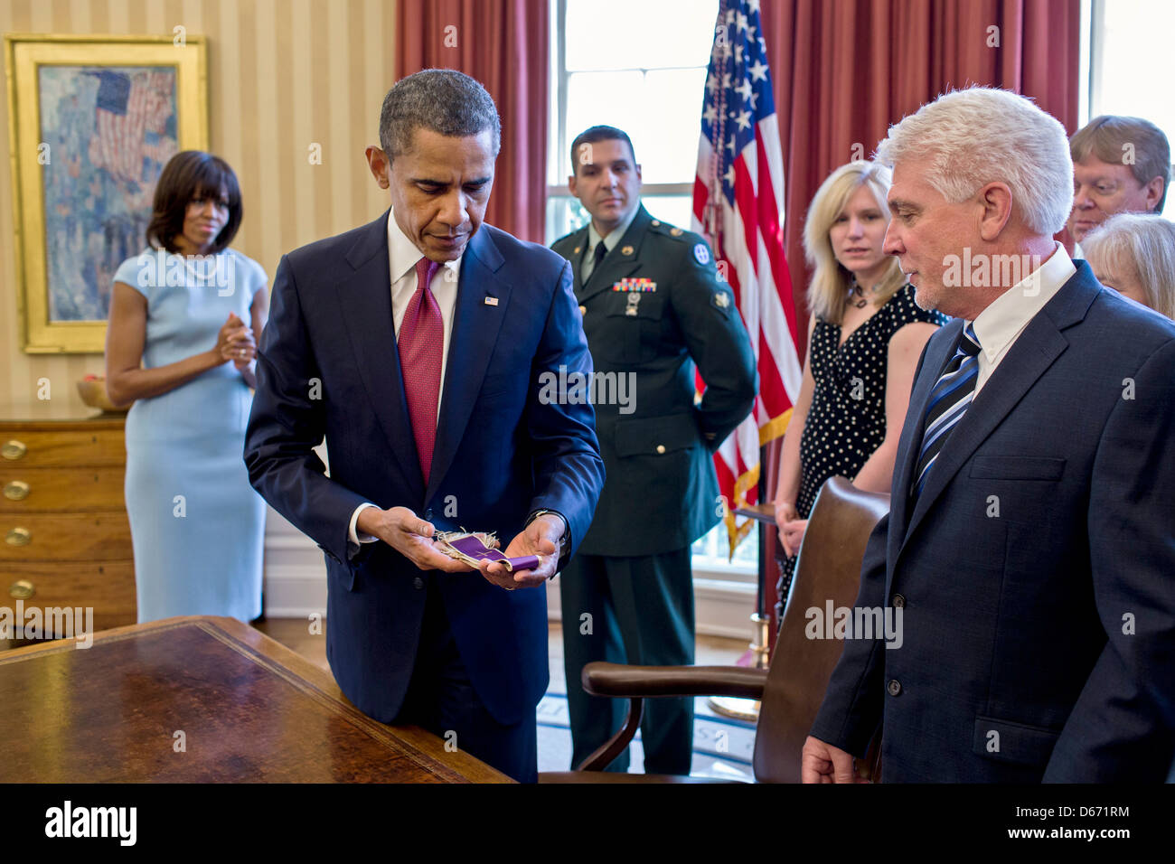 US President Barack Obama holds Father Emil Kapaun's Easter stole while meeting with the Kapaun family in the Oval Office of the White House April 11, 2013 in Washington, DC. The President and First Lady Michelle Obama met with members of the family before awarding him the Medal of Honor posthumously during a ceremony in the East Room. Father Kapaun was honored for his heroism during combat at Unsan, Korea and later died as a POW. Stock Photo