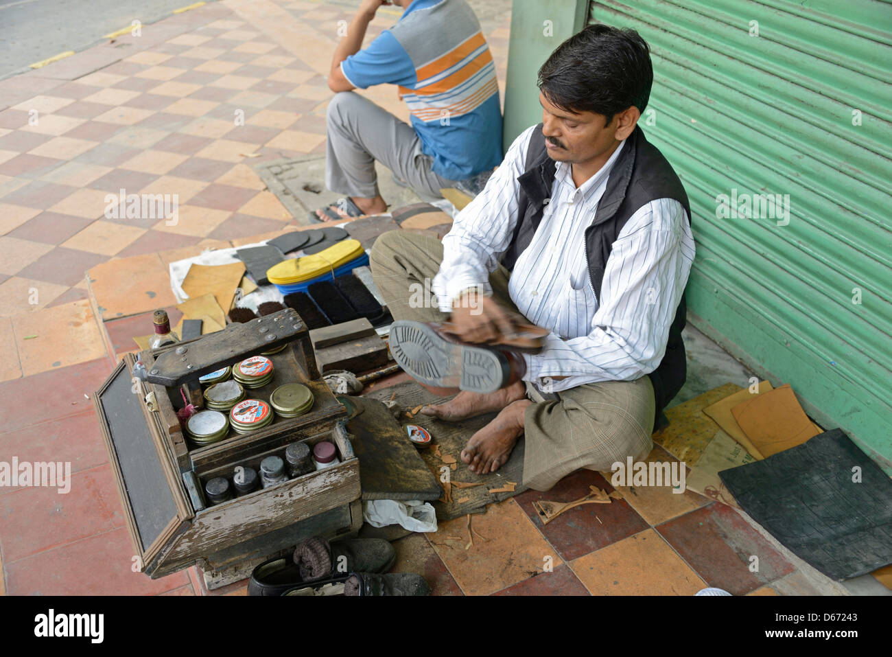 A shoe polisher with his shoe cleaning kit in a street in Delhi,India