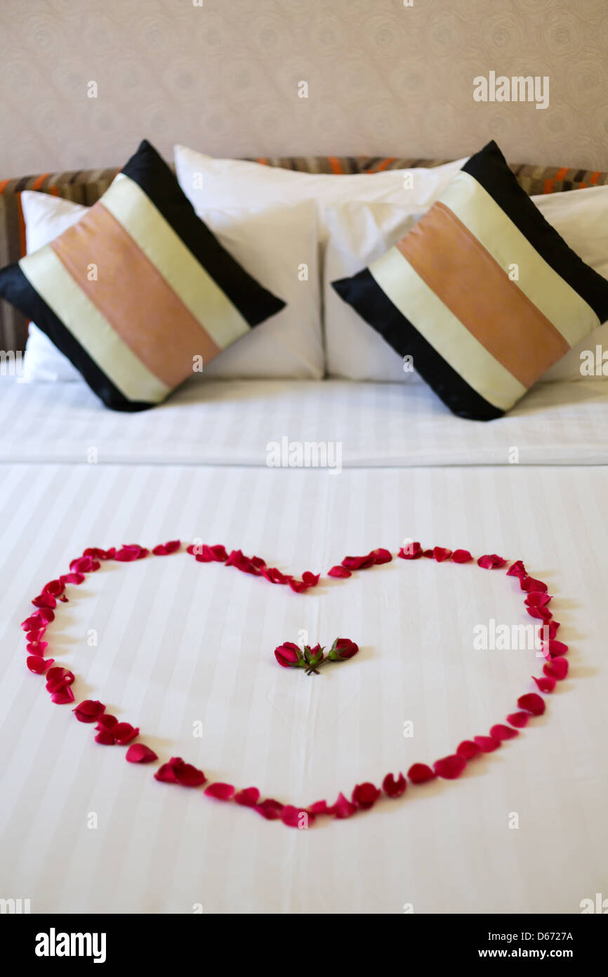 Heart of rose petals laid out on the bed, honeymoon Stock Photo