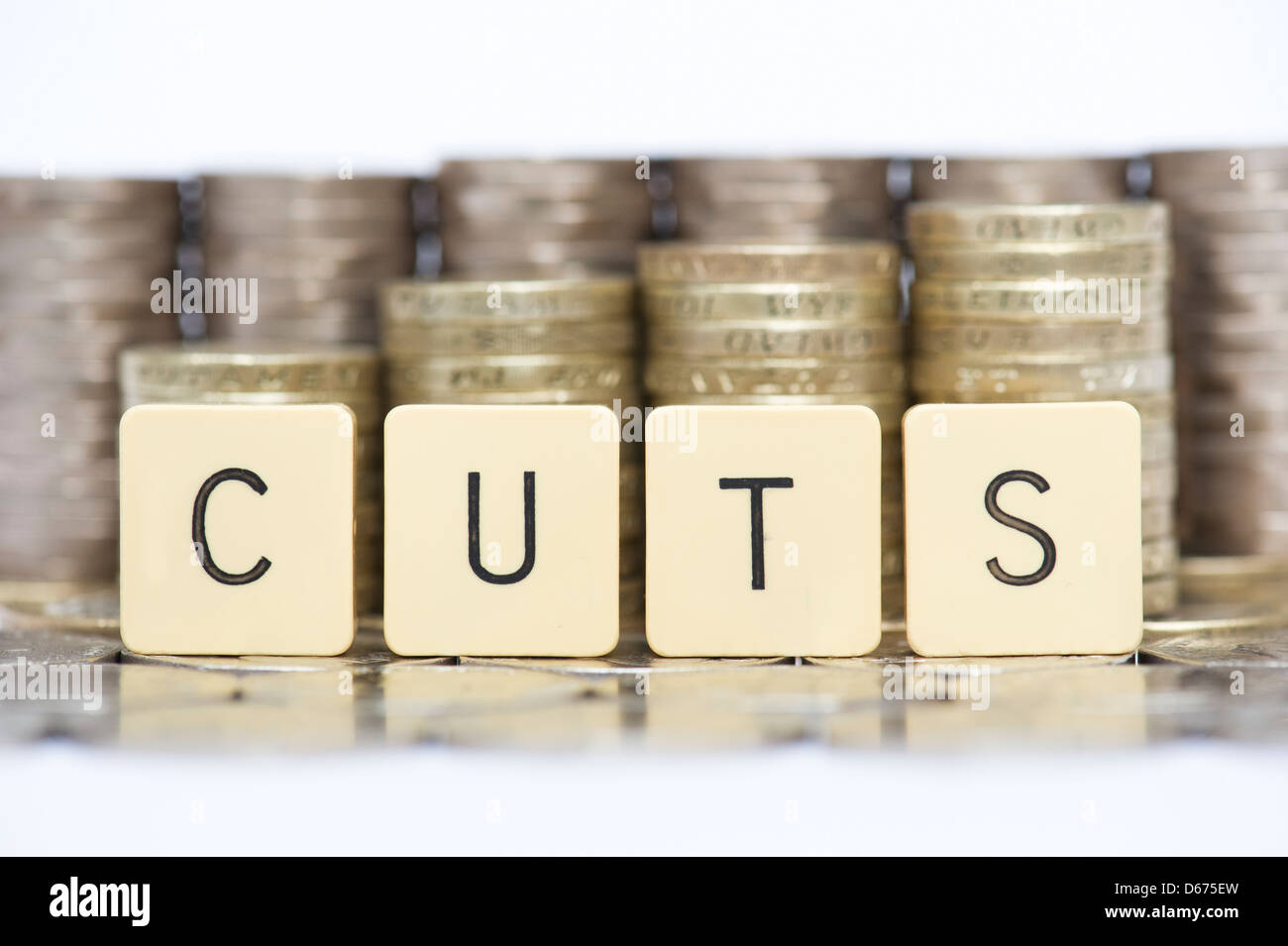 The word CUTS in front of stacks of English twenty pence and one pound coins Stock Photo