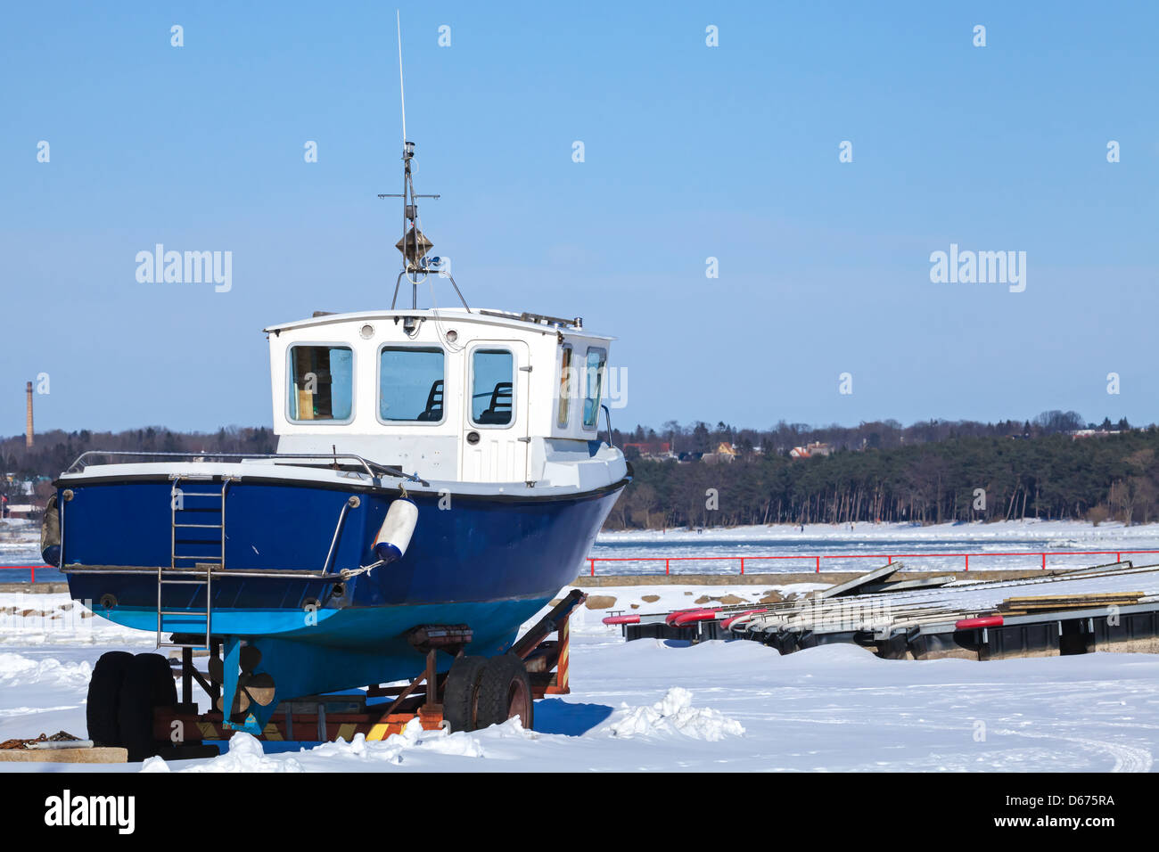 Small blue boat on the snowy coast of Baltic Sea in winter Stock Photo