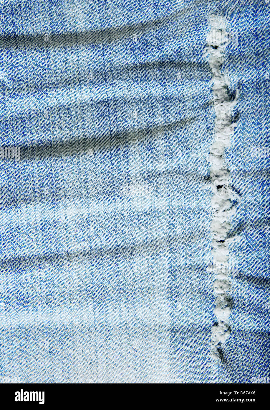 Worn out wrinkled denim fabric. Old blue jeans. Stock Photo