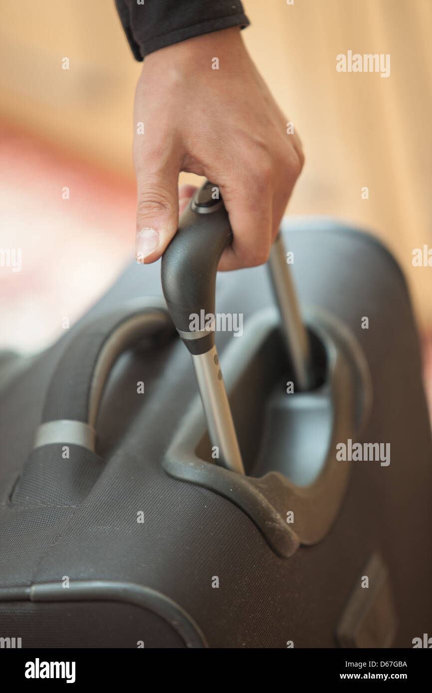 Man's hand holding the handle of a suitcase Stock Photo Alamy