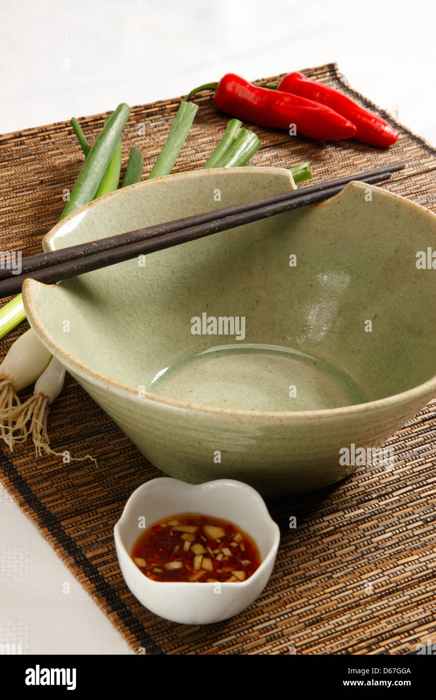 Asian  Chili chopsticks scallions spring onions empty bowl on a bamboo mat Stock Photo