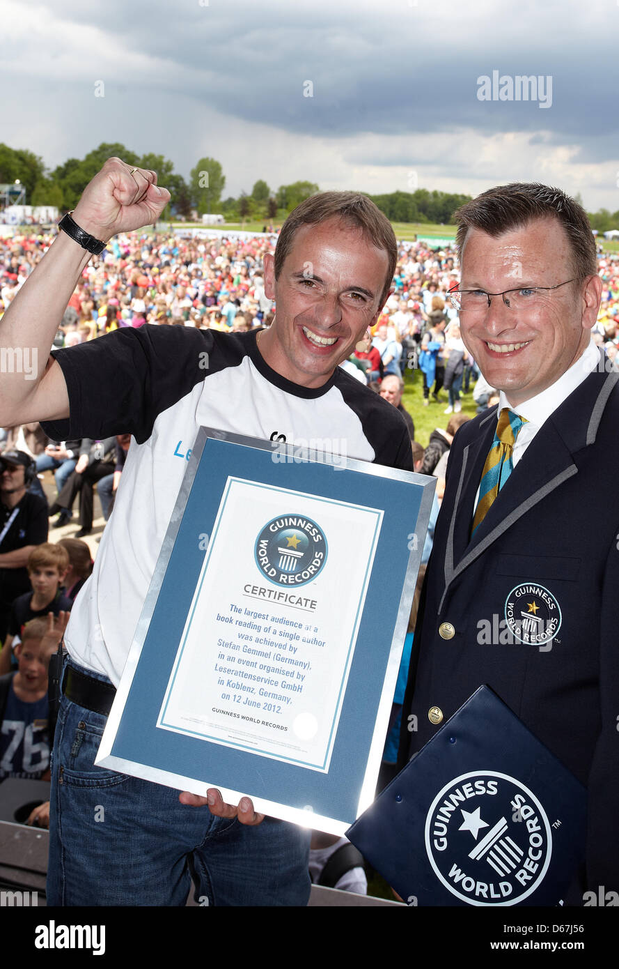 Children's book author Stefan Gemmel (L) receives the certificate for the read aloud world record from Guinness World Record judge Olaf Kuchenbecker in Koblenz, Germany, 12 June 2012. 5400 children were read to aloud by Gemmel for about one hour. This was the biggest crowd ever to listen to a reading of a single author in Koblenz. Photo: Thomas Frey Stock Photo
