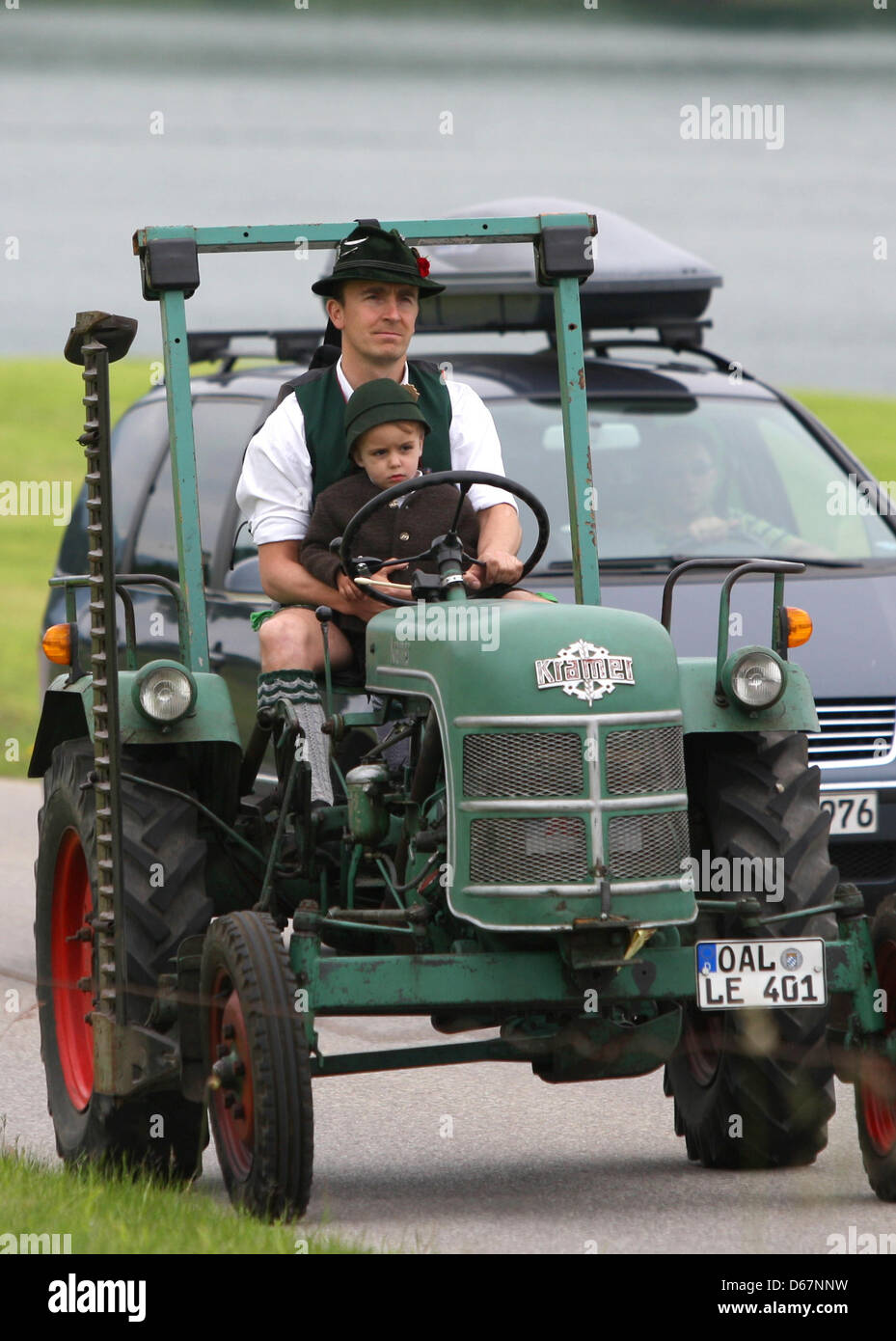 In traditional Bavarian garb, a man drives a tractor with his son during an oldtimer tractor meeting in Buching, Germany, 17 June 2012. Photo: Karl-Josef Hildenbrand Stock Photo