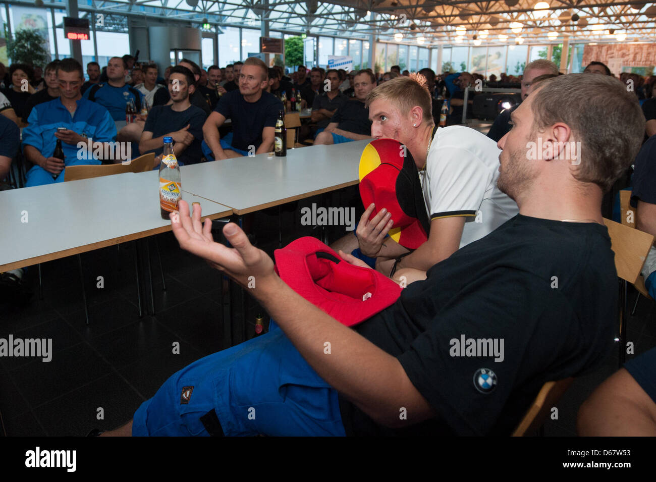 BMW employees watch the semi final match of the UEFA EURO 2012 between Germany and Italy  at the BMW factory in Regensburg, Germany, 28 June 2012. Around 2,500 staff members could watch the semi final match which was shown on three big screens. Photo: Armin Weigel Stock Photo