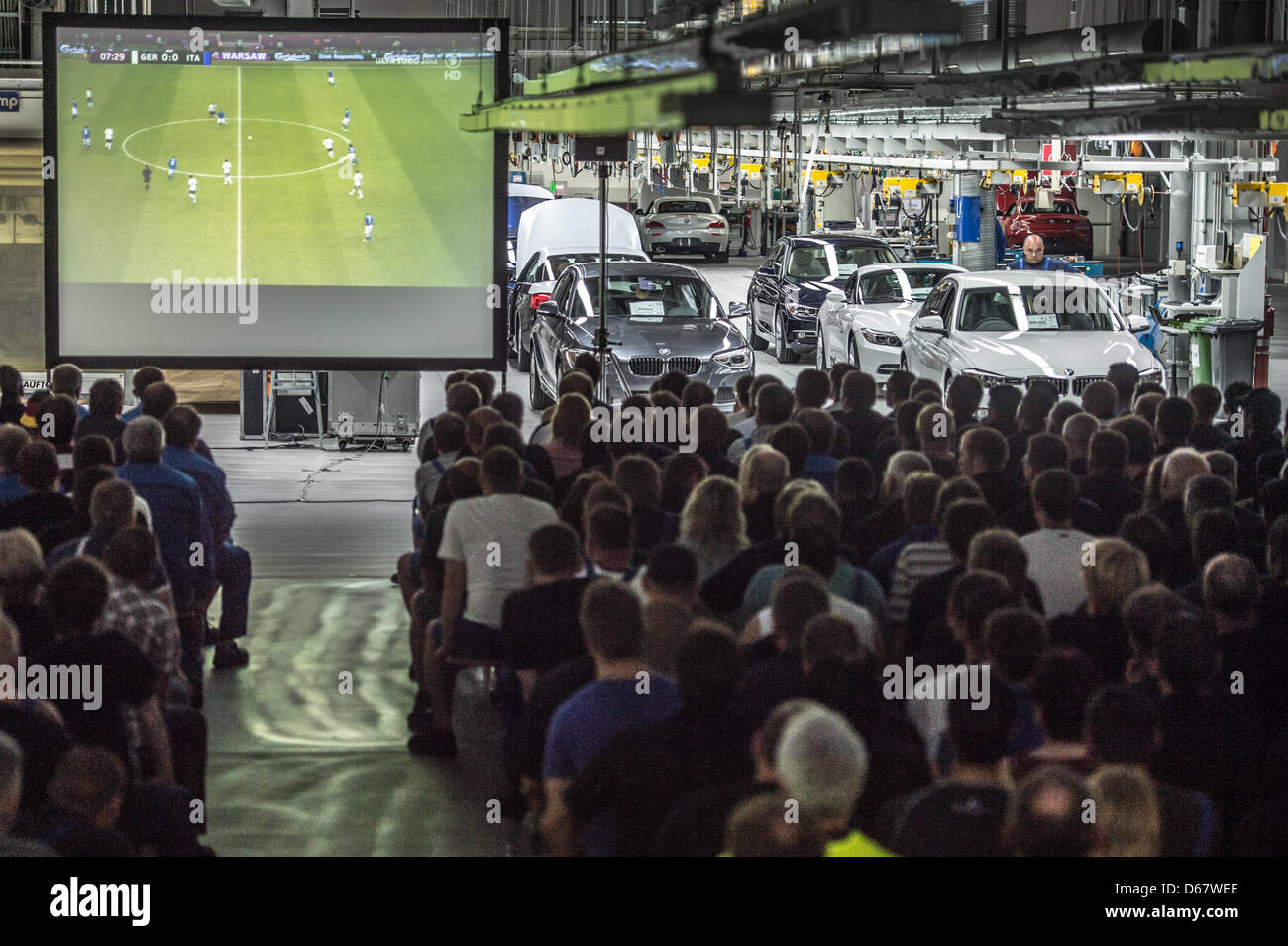 BMW employees watch the semi final match of the UEFA EURO 2012 between Germany and Italy  at the BMW factory in Regensburg, Germany, 28 June 2012. Around 2,500 staff members could watch the semi final match which was shown on three big screens. Photo: Armin Weigel Stock Photo