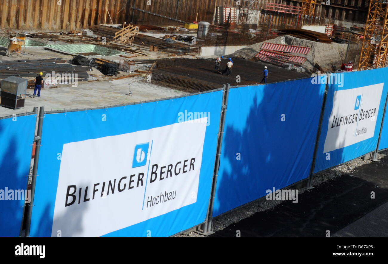 Bauarbeiter arbeiten am 28.06.2012 in München Riem an einer Baustelle während am Bauzaun das Logo des Bauunternehmens Bilfinger Berger zu sehen ist. Foto: Tobias Hase dpa Stock Photo