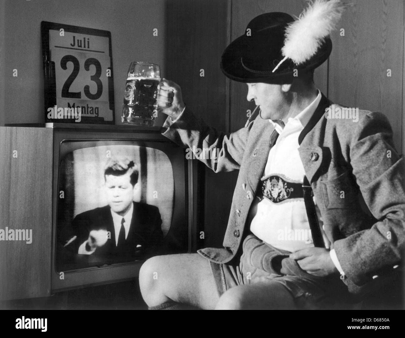 (dpa FILE) - An archive picture, dated 23 July 2012, shows a Bavarian man in traditional clothing cheering with a glass of beer while watching a live broadcast of US-President John F. Kennedy delivering a televised speech on his television set at his home in Bavaria, Germany, 23 July 1962. The civilian communications satellite Telstar was launched from Cape Canaveral on 10 July 196 Stock Photo