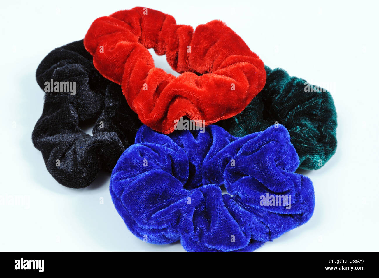 Four velvet hair scrunchies against a white background. Stock Photo