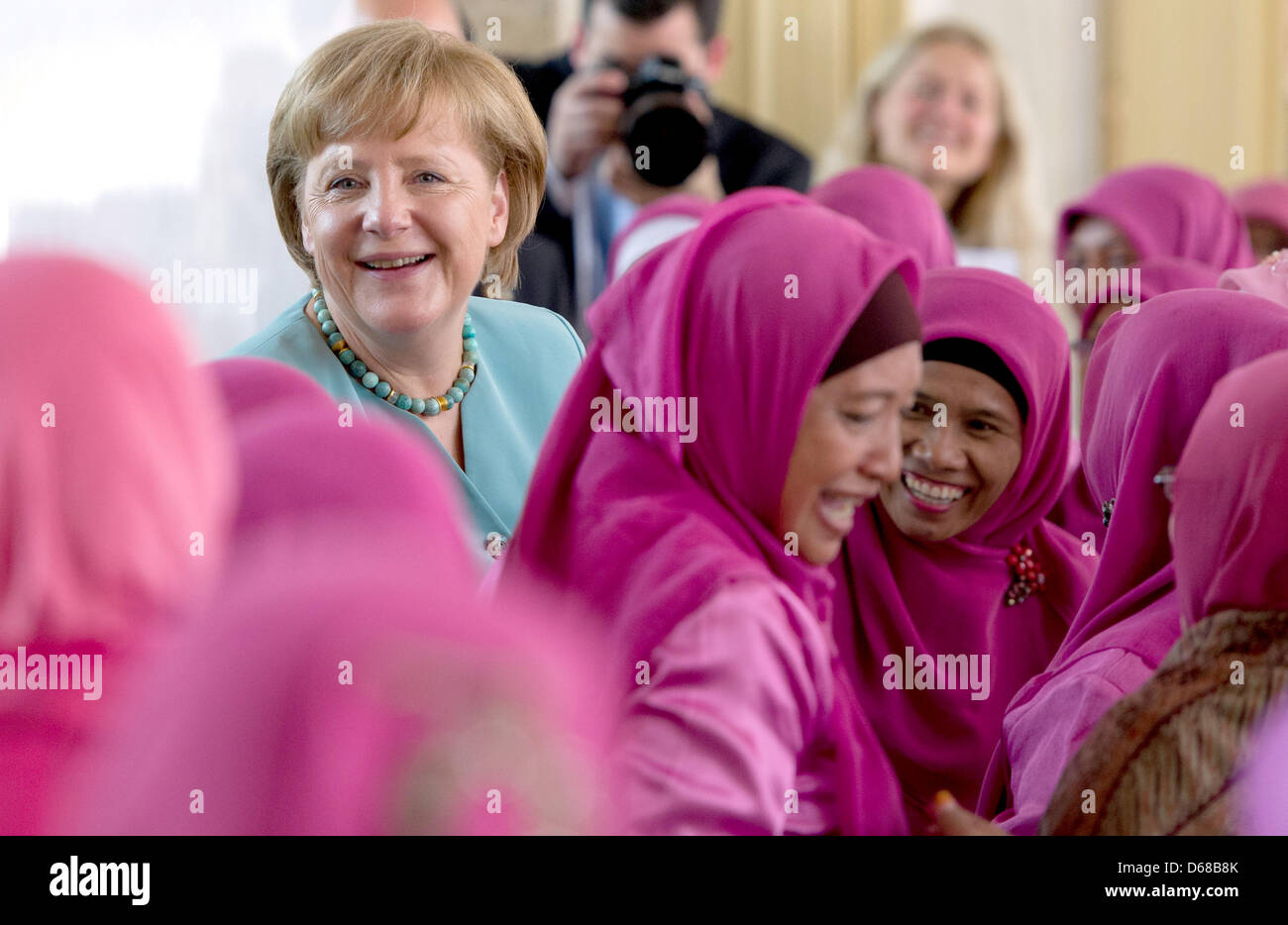 German Chancellor Angela Merkel (C) is surrounded by singing women as