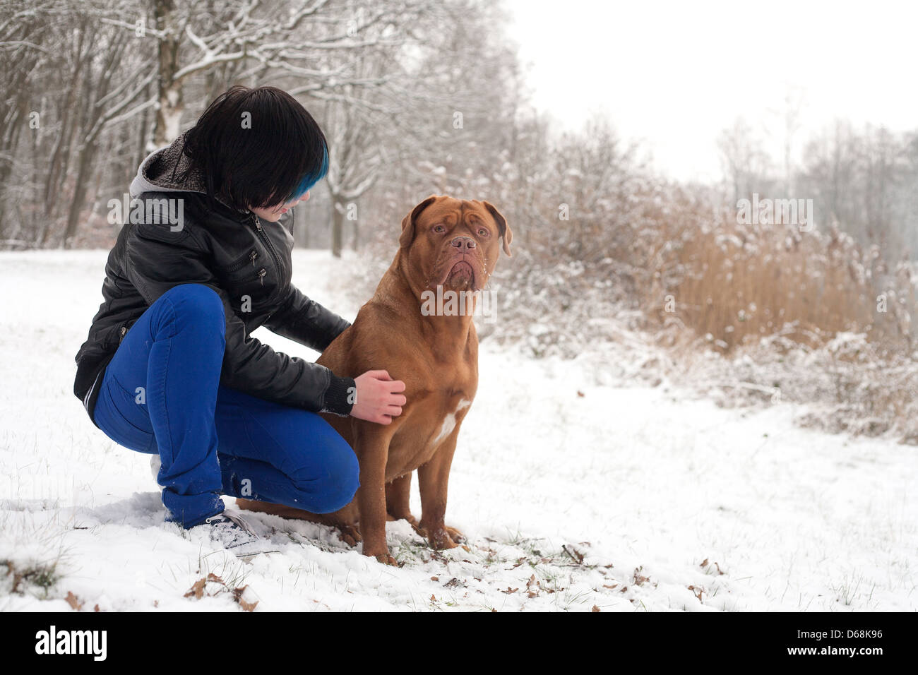 Funky boy is having fun with his dog in the snow Stock Photo