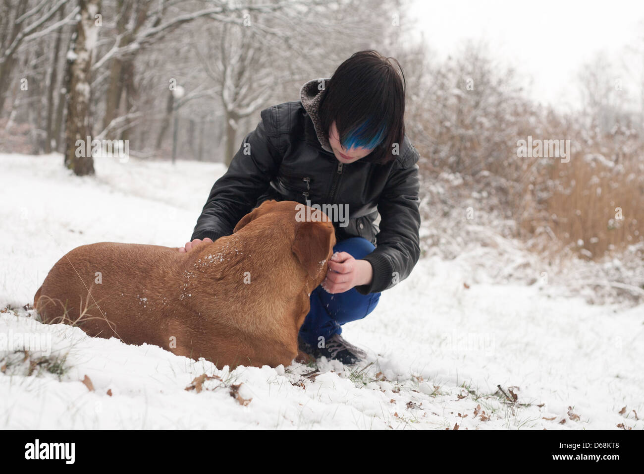 Funky boy is having fun with his dog in the snow Stock Photo