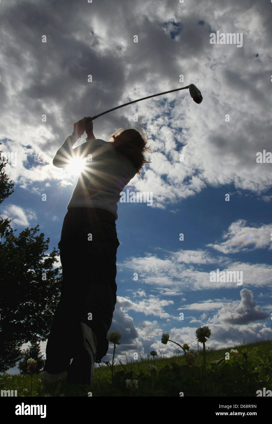 A woman swings her club under rip in the cloud cover at the Fleesensee golf course in Goehren-Lebbin, Germany, 20 July 2012. Photo: Heiko Lossie Stock Photo