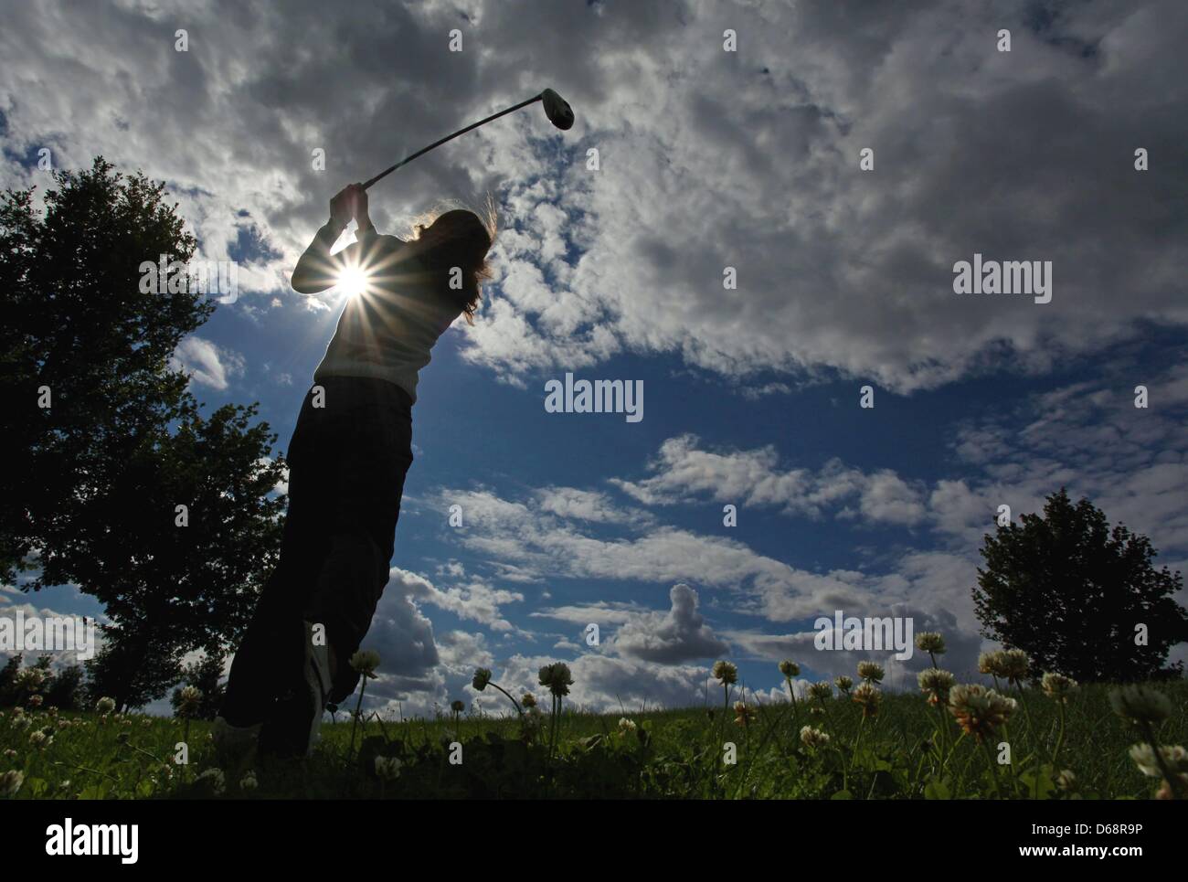 A woman swings her club under rip in the cloud cover at the Fleesensee golf course in Goehren-Lebbin, Germany, 20 July 2012. Photo: Heiko Lossie Stock Photo