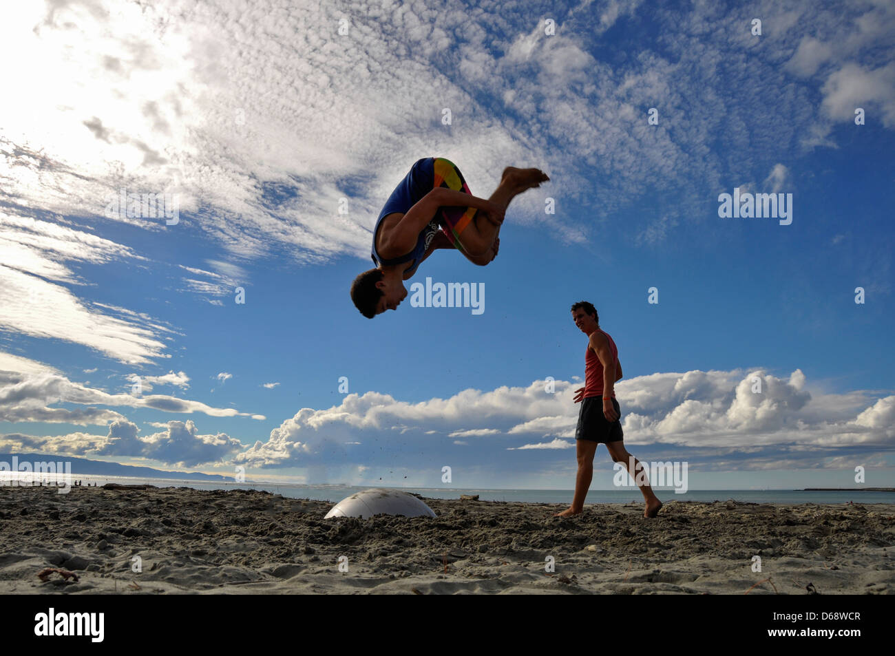 Young man somersaulting on the beach. Photographed in Nelson New Zealand. Model Re1lease Availanle Stock Photo