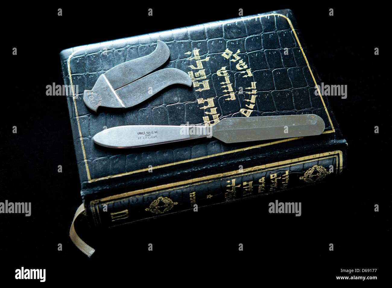 Instruments used in the Jewish religious circumcision ceremony brit milah, a knife and a foreskin guard, lie on a jewish prayer book in the rooms of the Israeli religious community in Hof, Germany, 26 July 2012. Photo: David Ebener Stock Photo